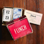 old Flinch Card Game - red Flinch box open with cards inside and instructions on wooden table.